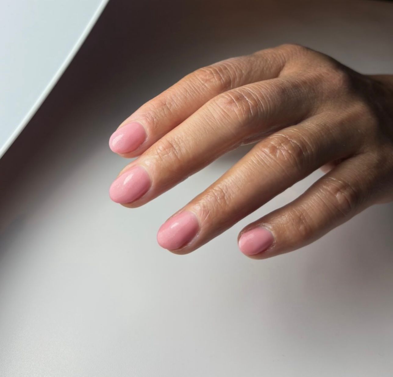 Korte roze nagels onder de witte nagellamp