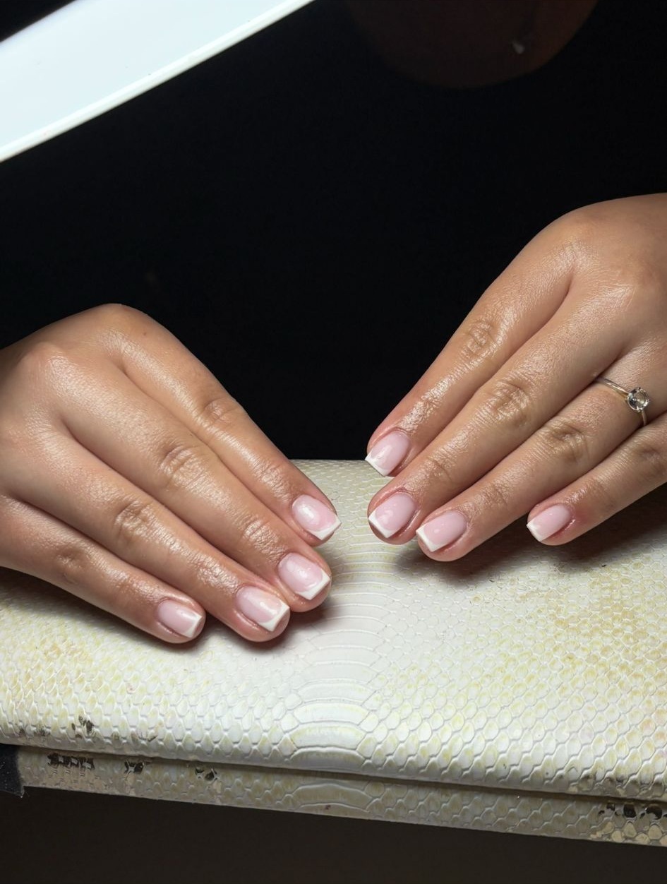 Twee handen met licht roze nagels op het crème kussen met slangenprint