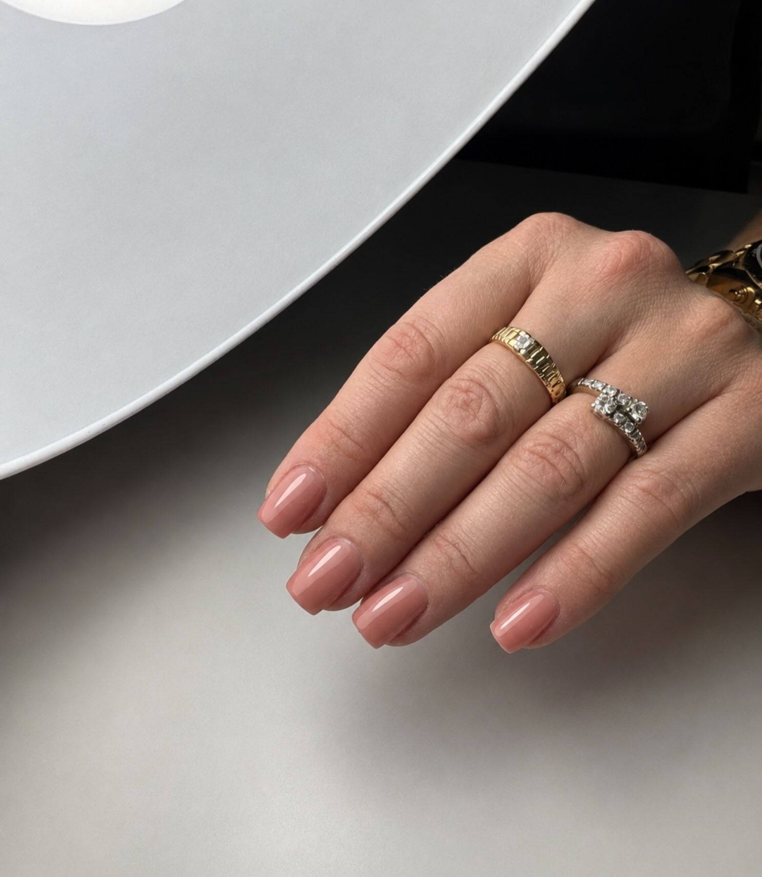 Glanzende nude nagels met gouden ringen