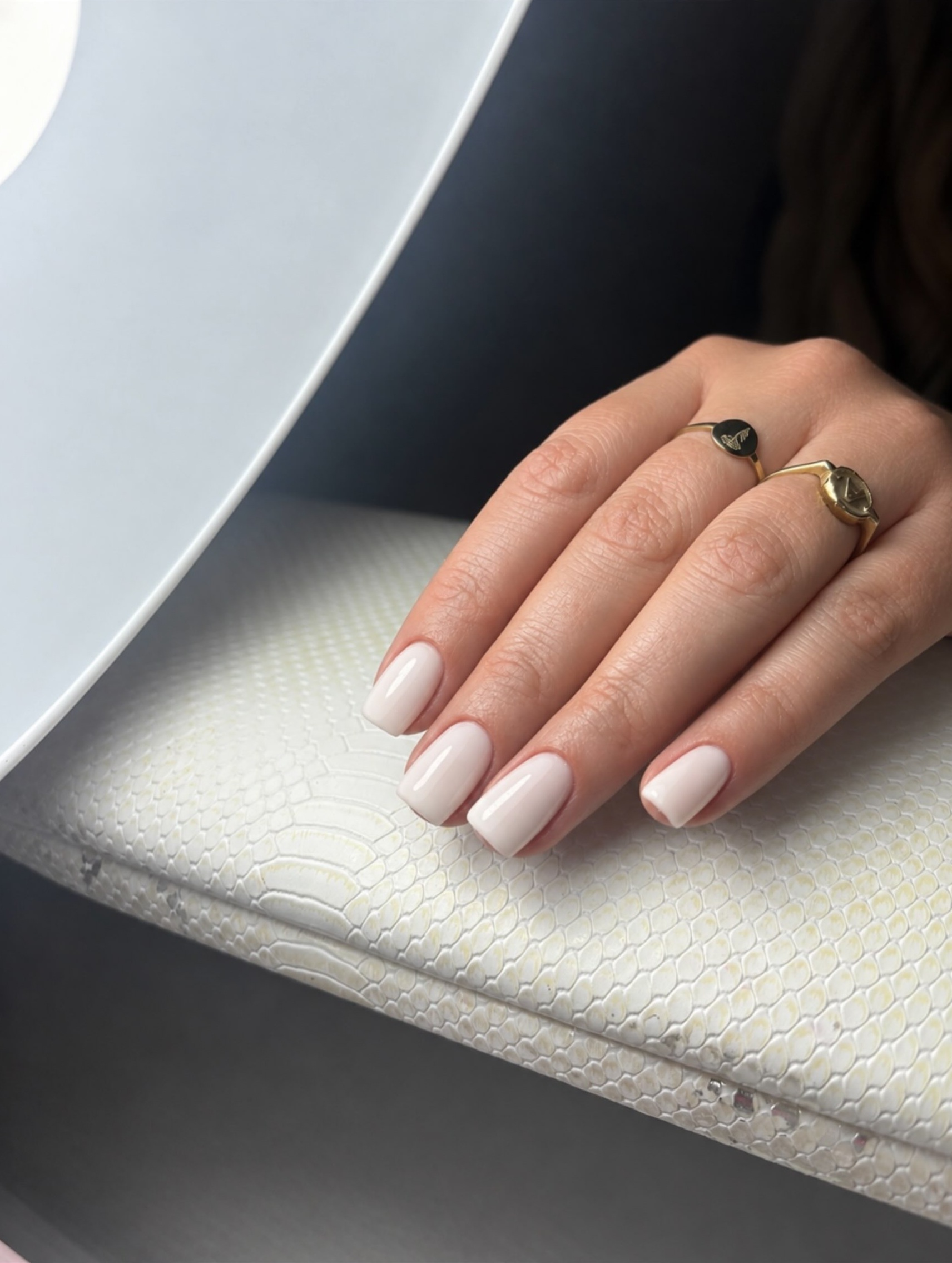 Melkwitte korte nagels op een crème kussen met slangenprint