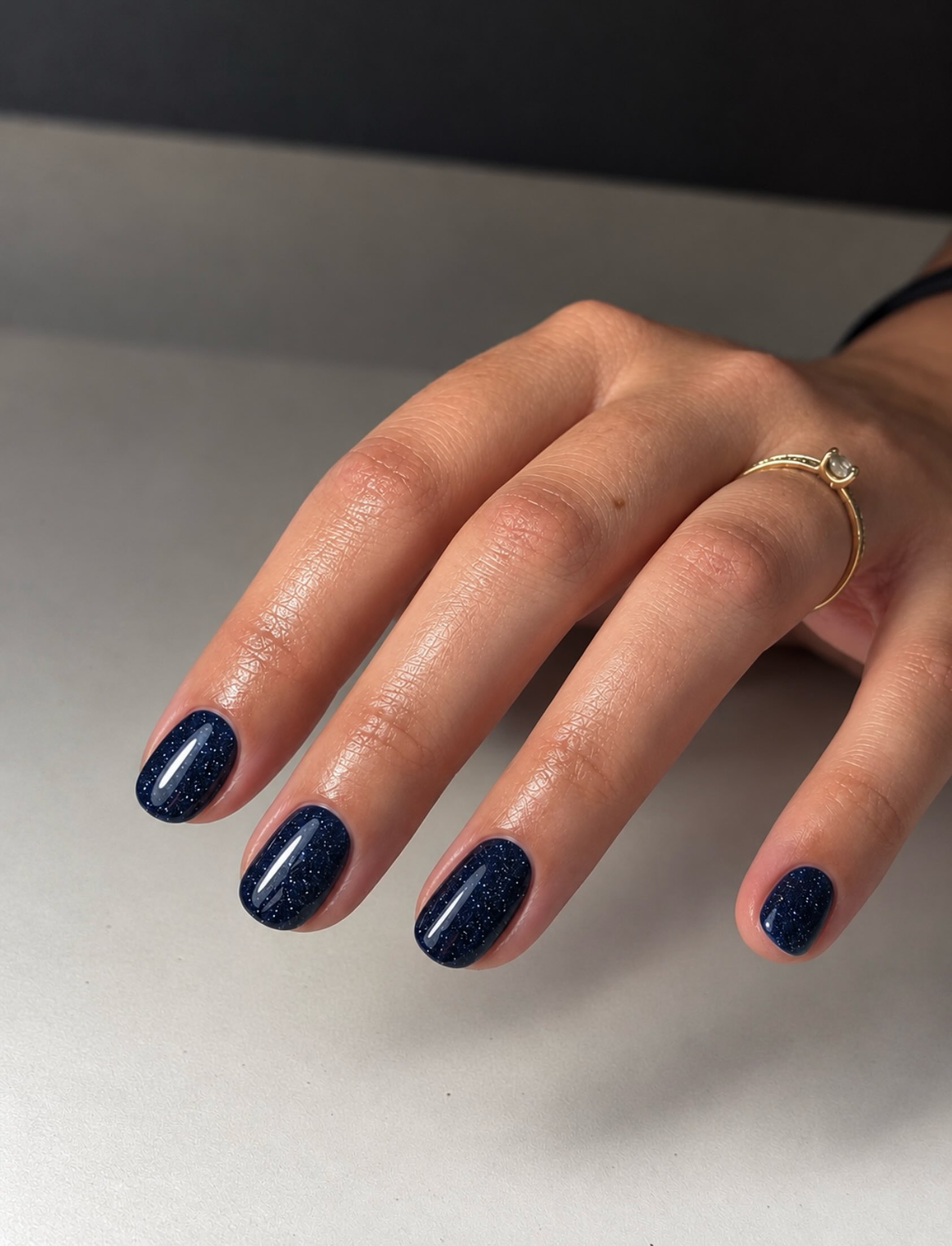 Donkerblauwe glitternagels op een grijze tafel